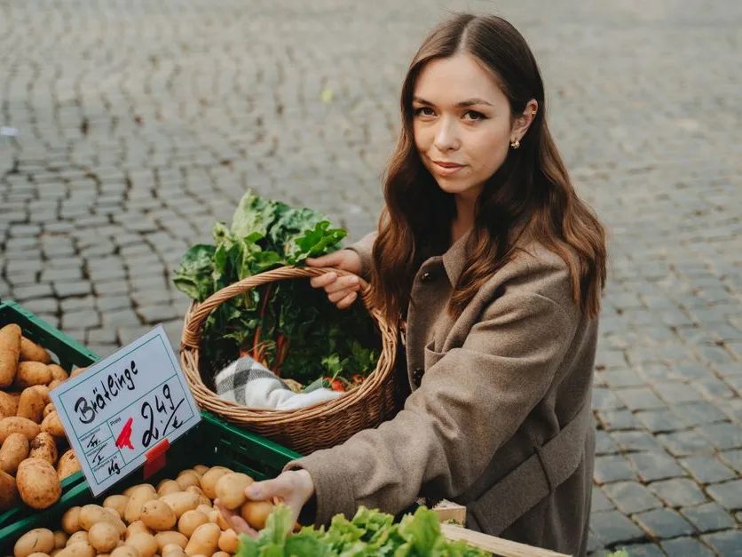 Une femme fait son marché, un panier de légumes frais à la main